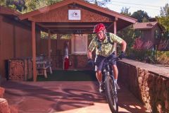 Man on bicycle with red helmet near wooden pavilion and foliage near Arabella Hotel Sedona in Sedona, AZ