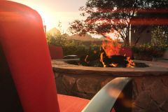 Red chair in front of outdoor fire pit with trees in background at sunset at Arabella Hotel Sedona in Sedona, AZ