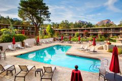 Pool with chairs and tables surrounding it in front of hotel with trees and foliage around the perimeter at Arabella Hotel Sedona in Sedona, AZ