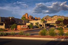 Exterior shot of Arabella Hotel Sedona in Sedona, AZ in front of mountains with clouds overhead in front of road