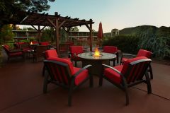 Group of red chairs around an outdoor fire pit with pavilion and mountains in background at Arabella Hotel Sedona in Sedona, AZ