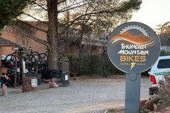 Thunder Mountain Bikes sign near tree and row of bikes near white pickup truck near Arabella Hotel Sedona in Sedona, AZ