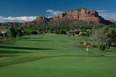 Golf course green with white flag sticking up near sand trap and water with mountains and trees in background near Arabella Hotel Sedona in Sedona, AZ