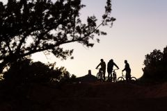 Silhouette of people riding bikes with trees and foliage and rocks in background at sunset near Arabella Hotel Sedona in Sedona, AZ