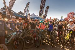 Sedona Mtn Bike Fest March 2023 Large group of people riding mountain bikes preparing for race with racing banners waving near trees near Arabella Hotel Sedona in Sedona, AZ