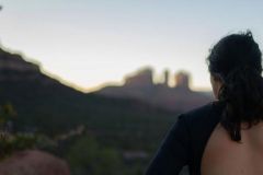 A woman at a yoga festival with her back towards the camera looks at the mountains in Sedona, AZ.