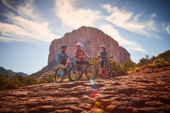 Three people wearing helmets on their bikes in the red rocks near the Arabella Hotel in Sedona, AZ.