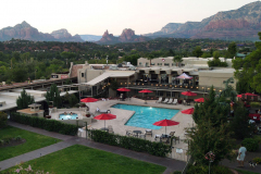 A swimming pool area with mountains and red rocks in the background at the Arabella Hotel in Sedona, AZ.