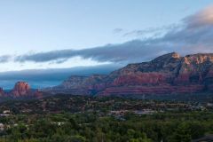 Encroaching grey clouds over red rock mountains and desert with trees and forest below mountains near Arabella Hotel Sedona in Sedona, AZ