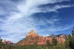 Blue skies with wispy clouds and trees in front of red rocks mountains near Arabella Hotel Sedona in Sedona, AZ