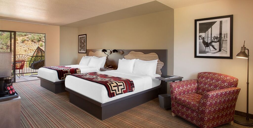 Bedroom with two beds, two chairs, and a patio with furniture at the Arabella Hotel in Sedona, AZ.