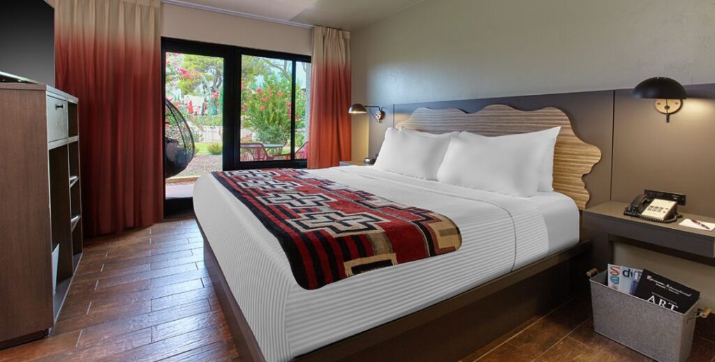 Bedroom with one bed, one chair and a patio with furniture at the Arabella Hotel in Sedona, AZ.