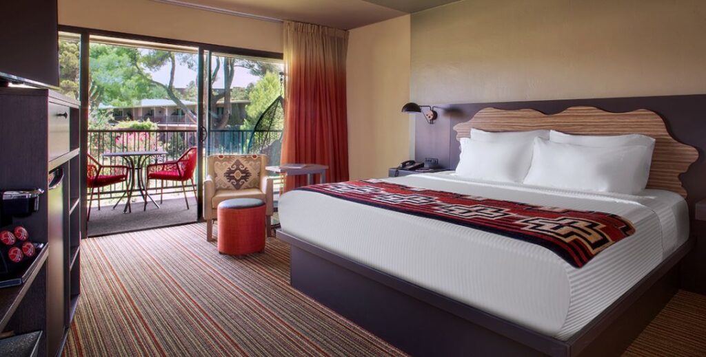 Bedroom with one bed with a chair and an outdoor patio with furniture at the Arabella Hotel in Sedona, AZ.