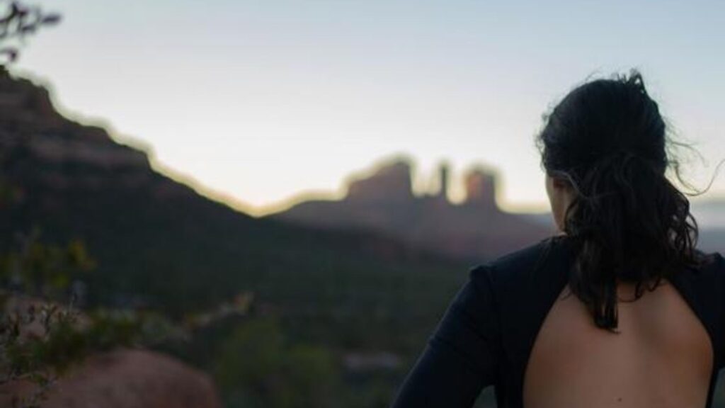 A woman at a yoga festival with her back towards the camera looks at the mountains in Sedona, AZ.