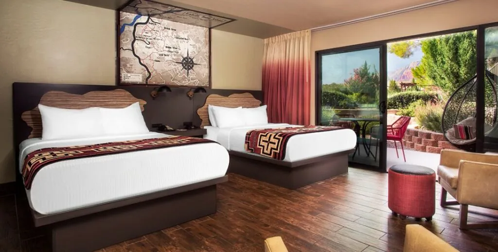 Bedroom with two beds and an outdoor patio with furniture at the Arabella Hotel in Sedona, AZ.