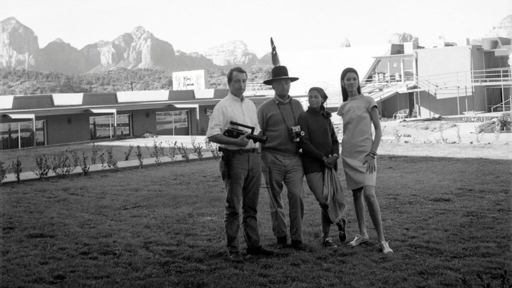 Group of people standing in front of hotel building with mountains in background while man in front takes a picture at Arabella Hotel Sedona in Sedona, AZ