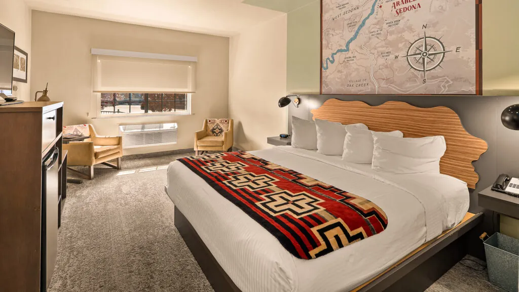 A hotel room with a large bed, sitting area, and a map on the wall.