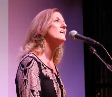 A woman singing into a microphone on stage at Arabella Hotel Sedona.